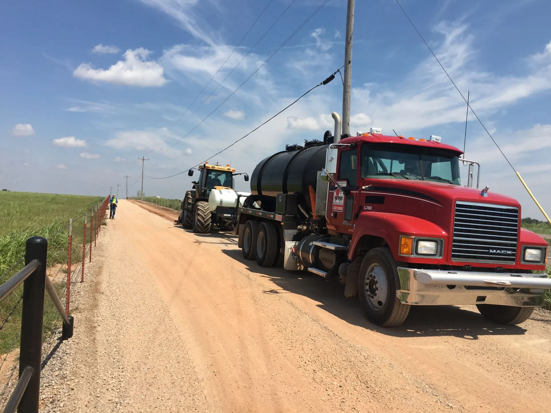 Water truck and tractor lined up on a gravel road
