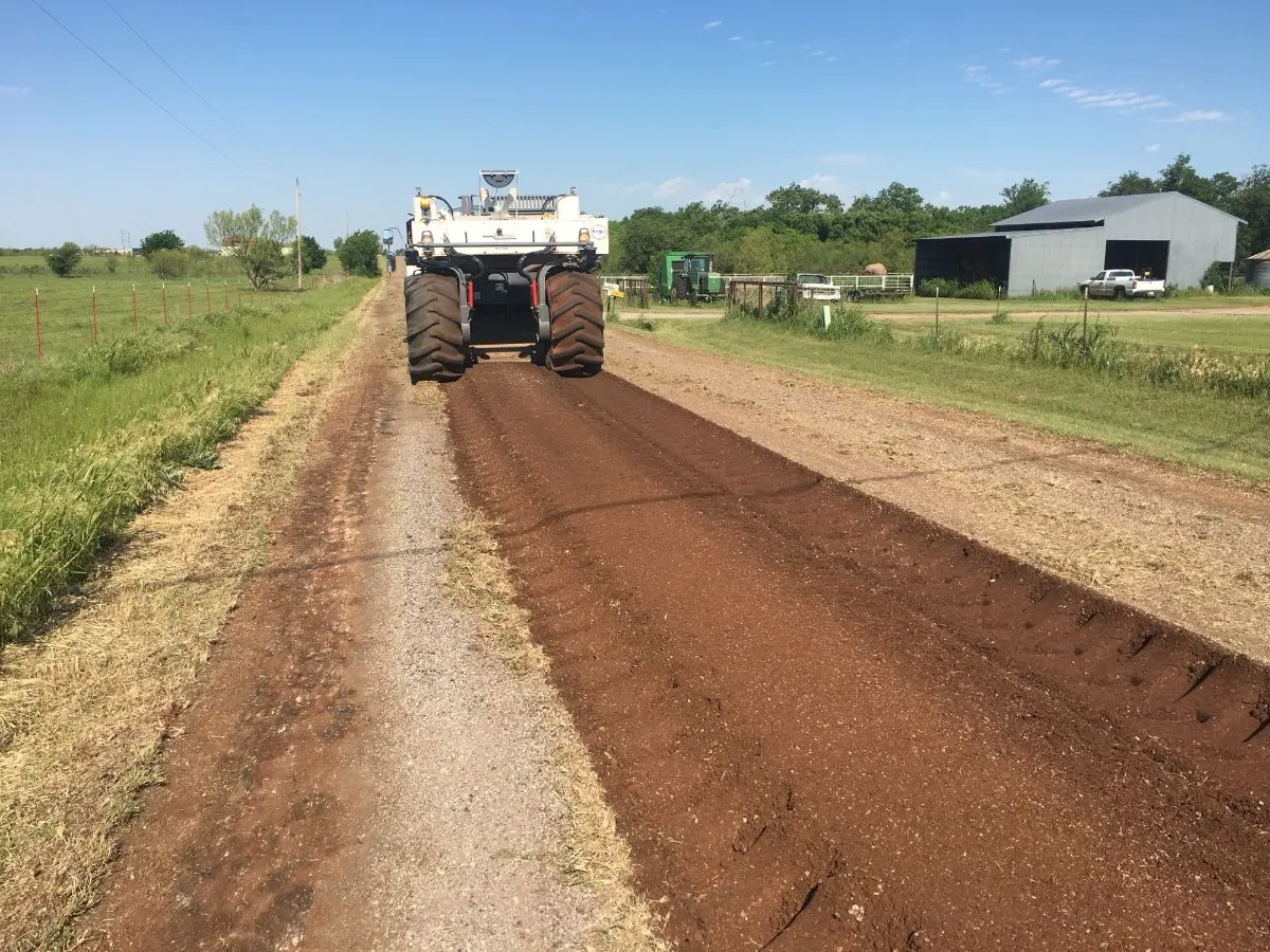 Reclaimer tilling stabilizer into a gravel county road
